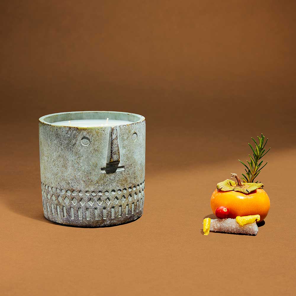 Hand-painted cement planter styled as a peaceful human face, serving as a decorative home candle vessel.