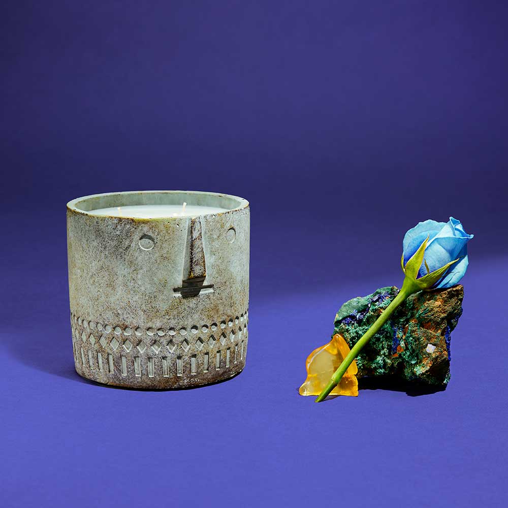 Close-up of the stone face candle showing textured cement and smooth hand-painted features.