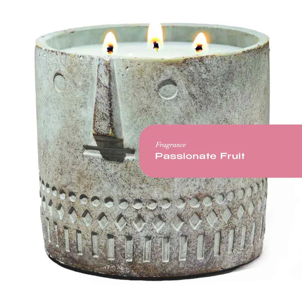Hand-painted cement vessel candle with a stone face design, natural cement color.