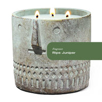 Hand-painted cement vessel candle with a rustic face design on a wooden surface