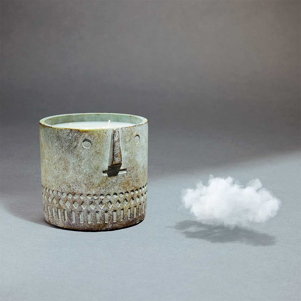 Side view of the unscented stone face candle in a cement vessel showing smooth finish and size scale.