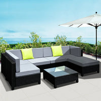Wide-angle view of complete 7-piece outdoor wicker furniture set in patio environment.