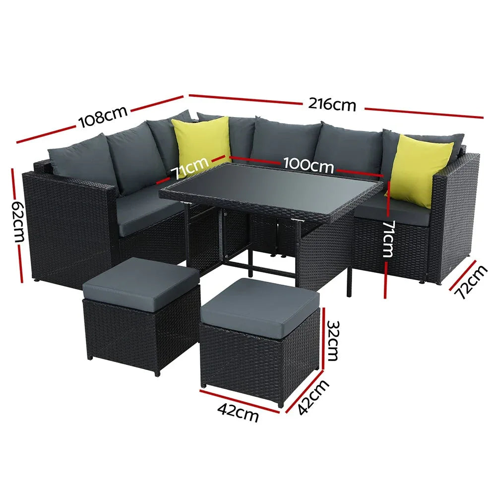 Side view of black woven rattan outdoor sofa with thick cushions and ottoman on a patio.
