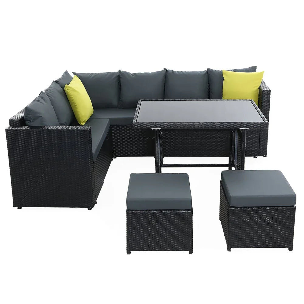 Corner arrangement of black outdoor wicker patio seats with beige cushions near a wall.