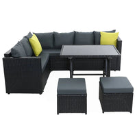 Corner arrangement of black outdoor wicker patio seats with beige cushions near a wall.