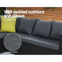 Modern black outdoor dining sofa set on stone floor with cream cushions and ottoman.