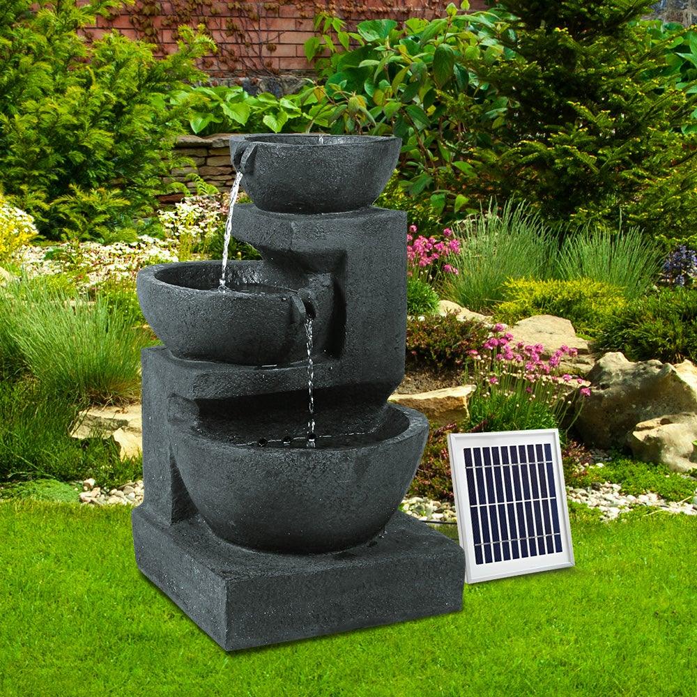Blue bird bath fountain placed outdoors with solar panel nearby on grass