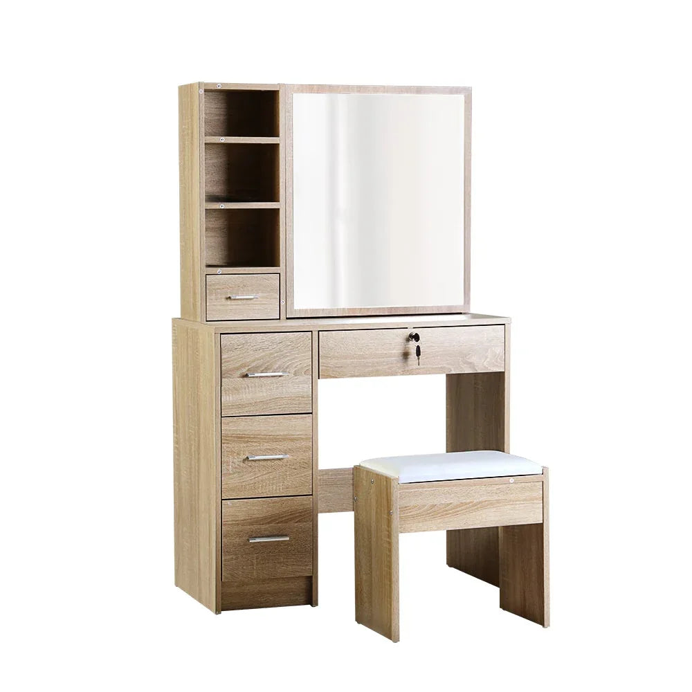 Wooden dressing table with large sliding mirror and drawers in bedroom setting.