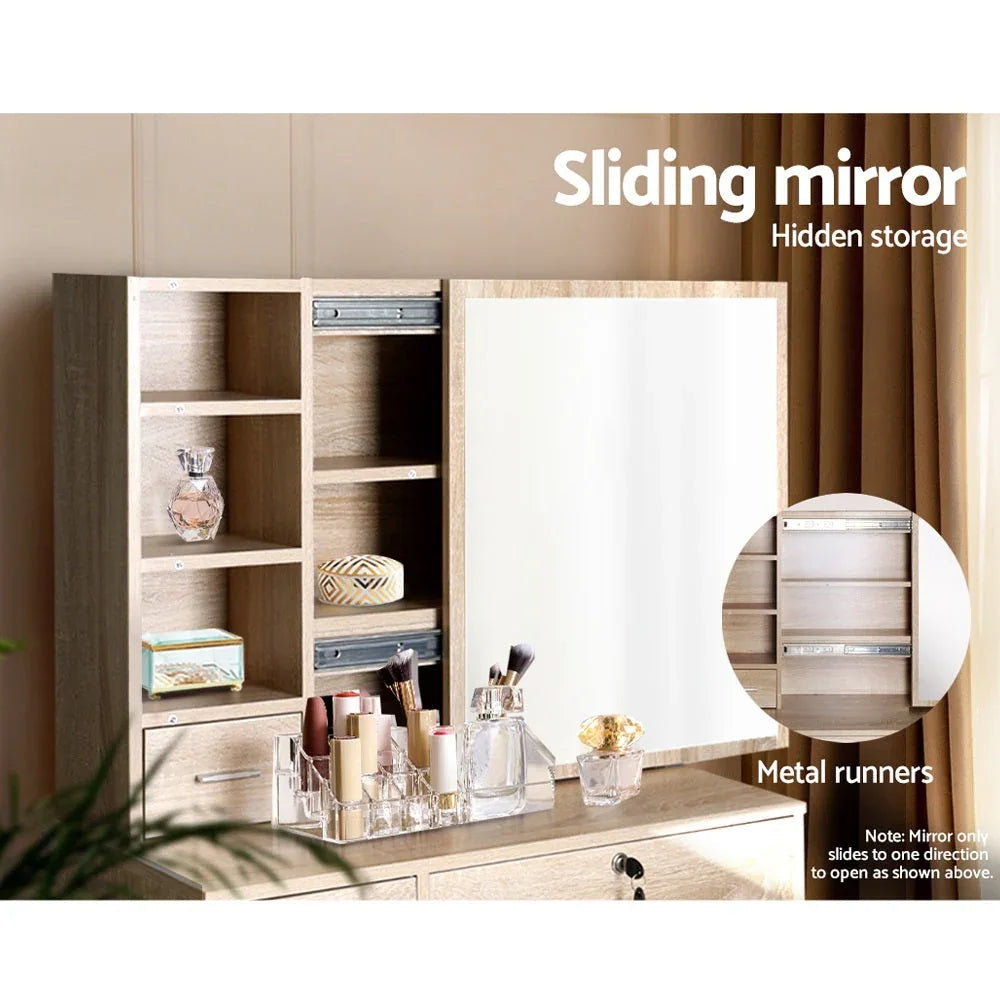Open storage drawers and shelves under dressing table with makeup items.