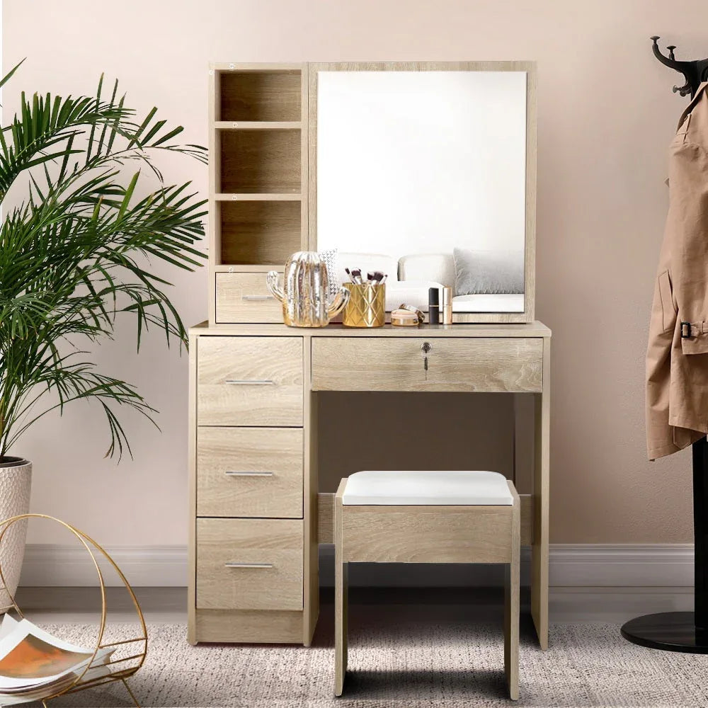 Wooden makeup vanity desk with chair and large mirror in bright room.