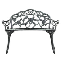 Close-up of floral-patterned backrest of green Victorian garden bench.