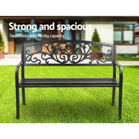 Close-up of powder-coated black iron legs of garden bench on concrete floor.