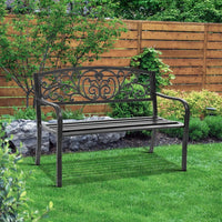 Black vintage-style garden bench on outdoor deck with greenery in background.