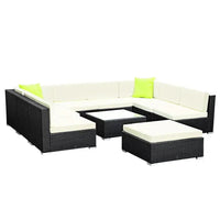 Corner view of outdoor furniture set arranged on patio with cushions and glass table