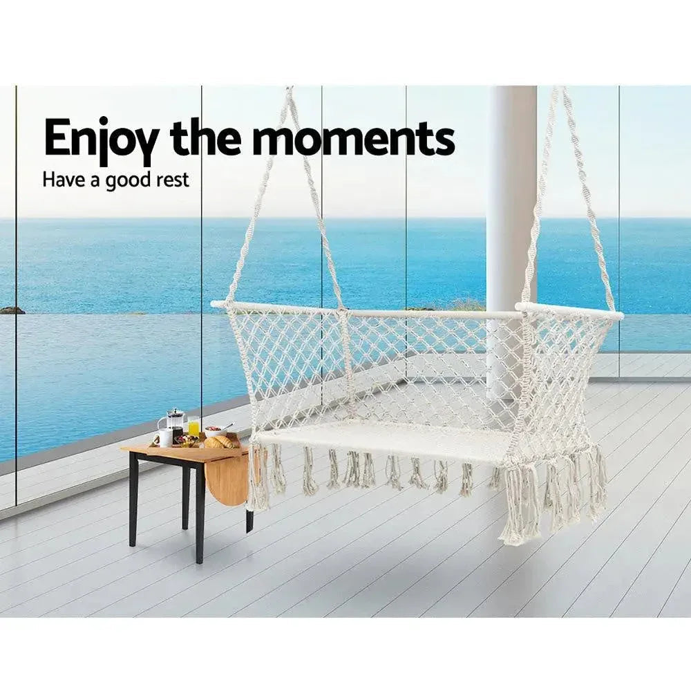 Side view of a double rope hammock chair with cream fabric and tassels.