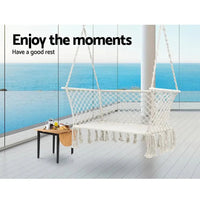 Side view of a double rope hammock chair with cream fabric and tassels.