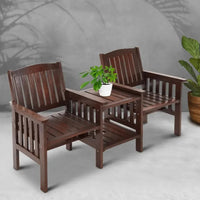 Wooden outdoor loveseat with spacious double-layer table in the middle, placed on patio flooring.