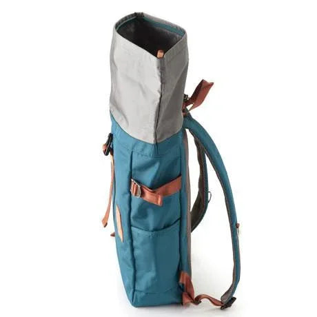 Side view of blue rolltop backpack highlighting size and arm holding shoulder strap.