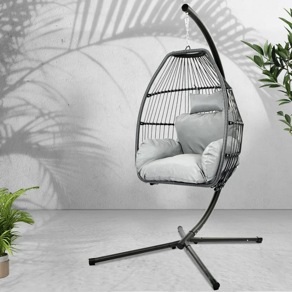 Full view of grey hammock-style hanging egg chair with stand and soft cushion indoors.