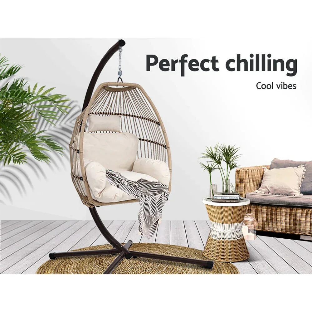 Front view of the wicker hanging egg chair with cushions on a patio setting.