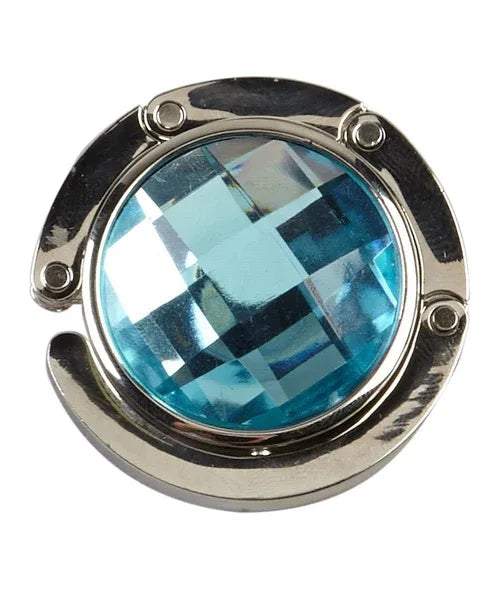 Blue handbag hanger folded closed displaying rhinestone center on white surface.