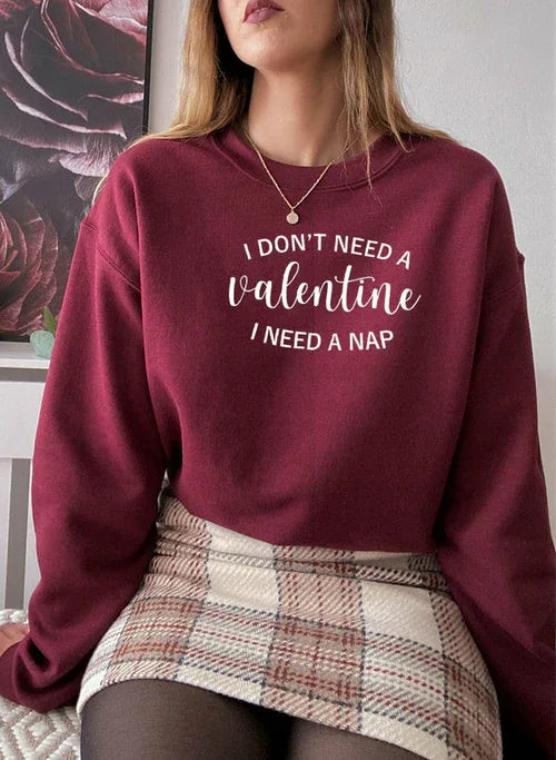 Close-up of man wearing black 'I Don't Need A Valentine' sweatshirt against plain background.