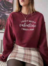 Close-up of man wearing black 'I Don't Need A Valentine' sweatshirt against plain background.
