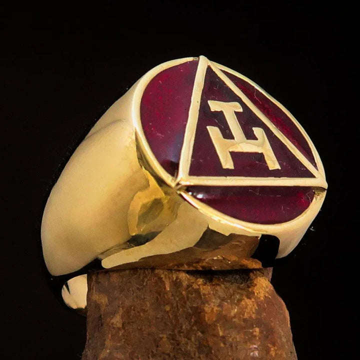 Close-up of a red enamel Masonic pinky ring with gold solid brass band on a black background.