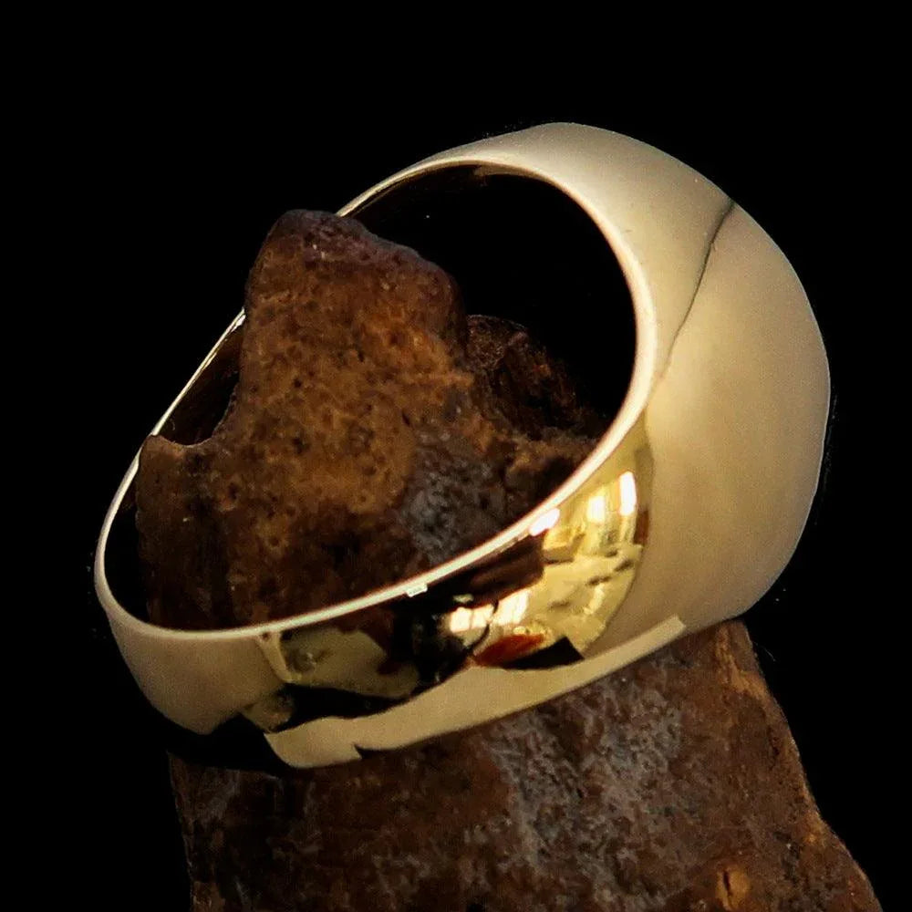 Solid brass men's red Masonic ring resting on a reflective surface, showing its thickness.