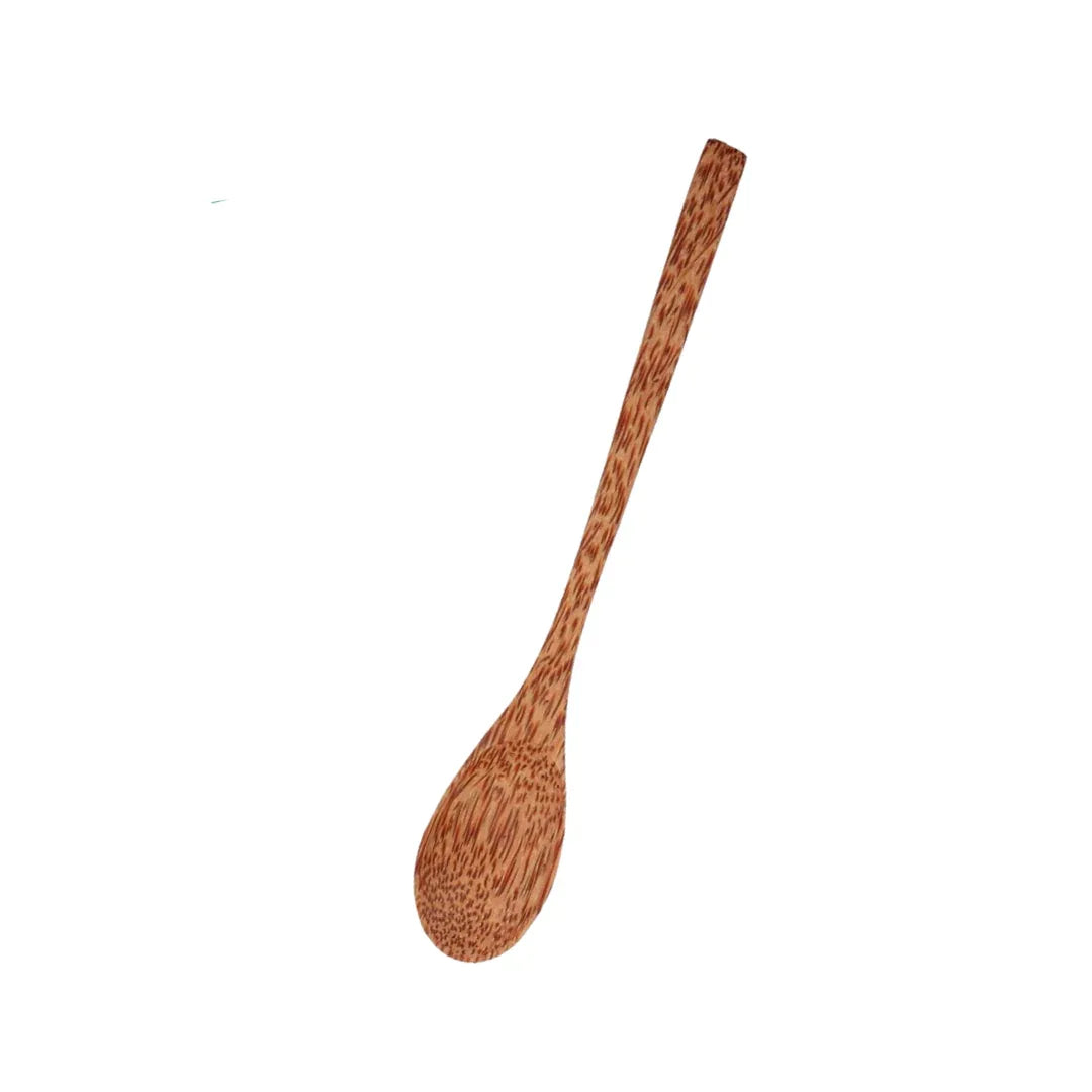 Stylish wooden coconut spoons arranged on a light wooden surface with green leaves background.