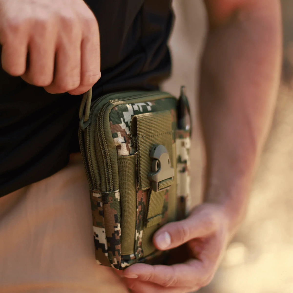 Black tactical MOLLE waist pouch with multiple compartments and durable straps laid flat on a gray background.