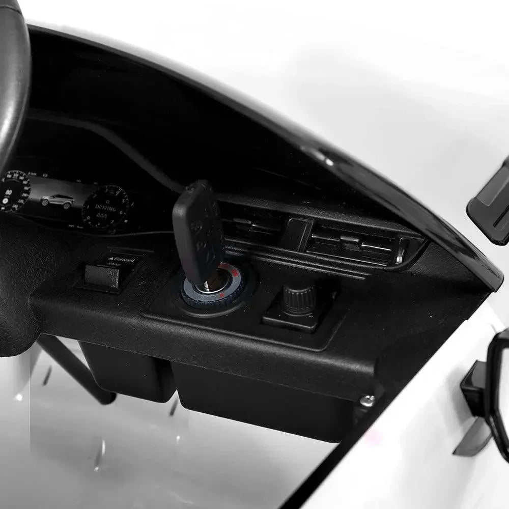 White kids ride on Land Rover car with remote control beside it on white background.