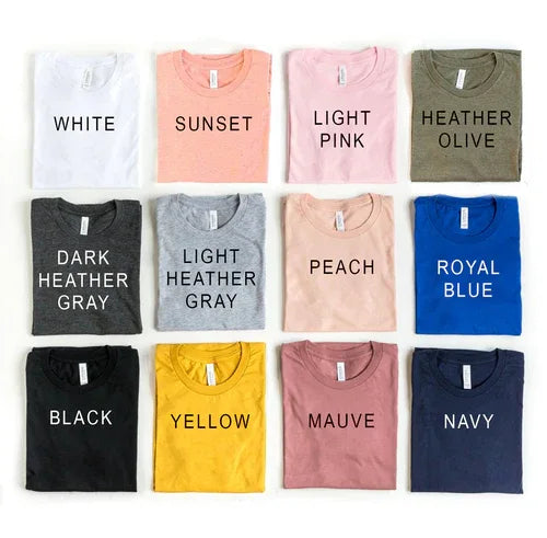 White #Momlife T-shirt hanging on wooden hanger against plain background