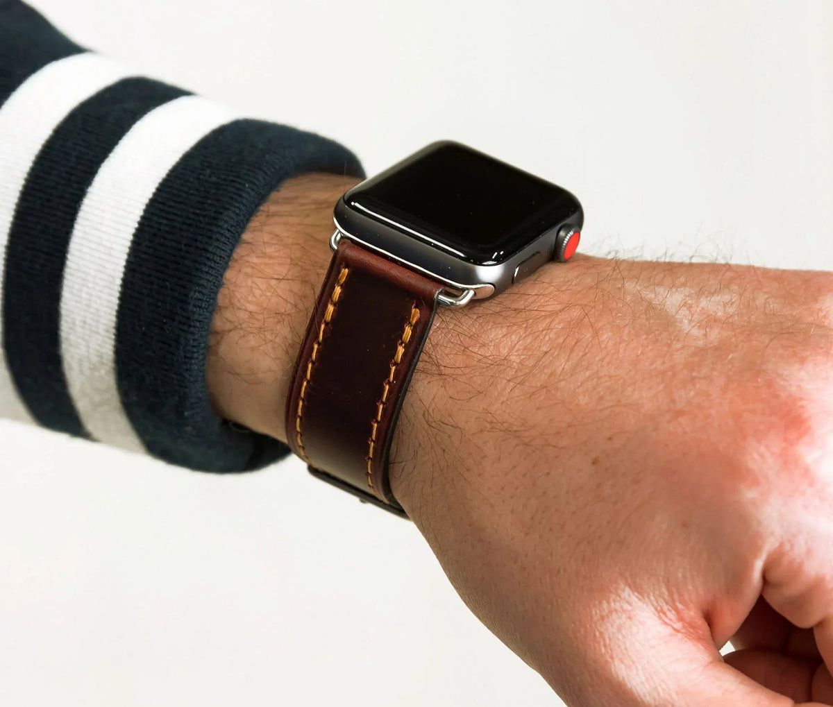 Close-up detail of leather texture and stitching on Apple Band Designer watch band in brown.