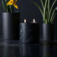 Matte black ceramic vessel of Dewy Schnozberry candle with a smooth round shape, set on white surface.