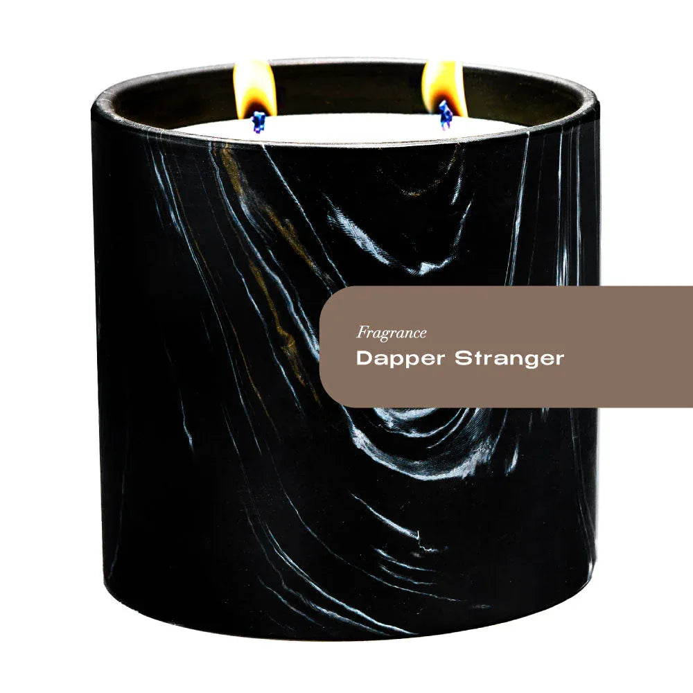 Hand-painted black ceramic candle vessel with white and gold Marquina swirl design, empty.