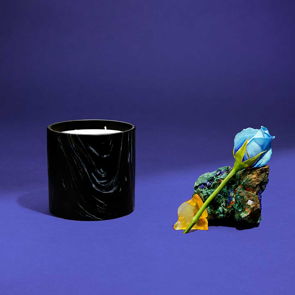 Close-up of hand-painted Marquina ceramic candle showing elegant black, white, and gold swirls
