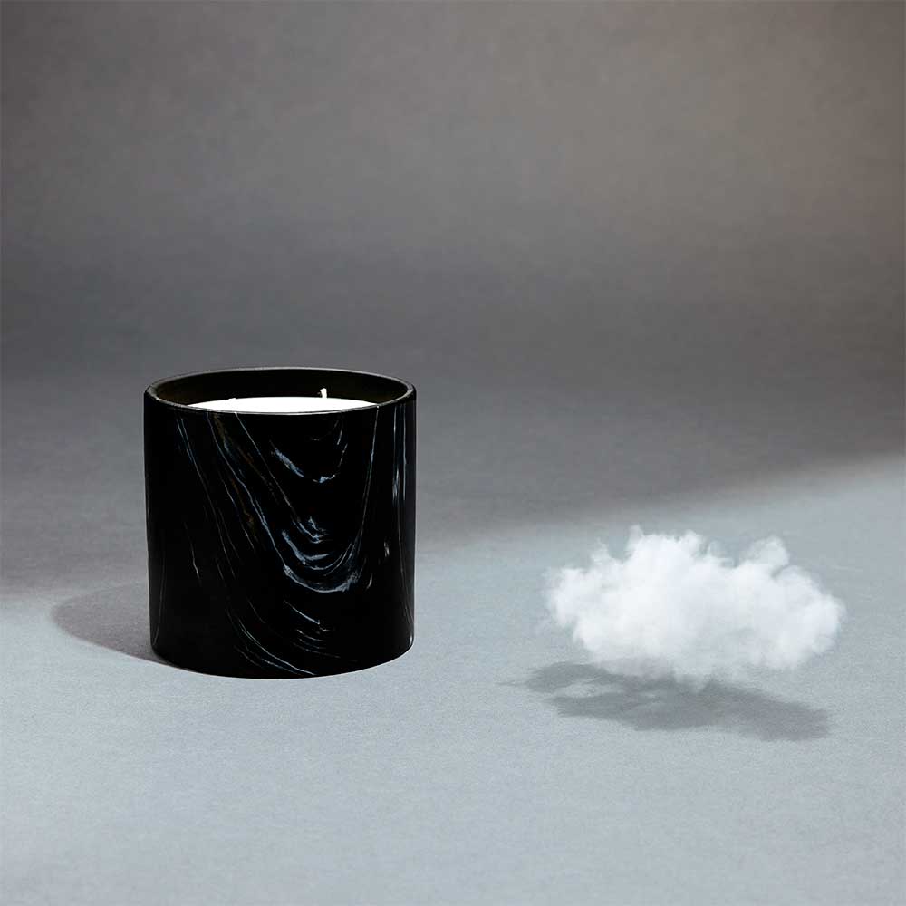 Close-up of black marquina ceramic candle showing intricate white and gold swirl patterns.