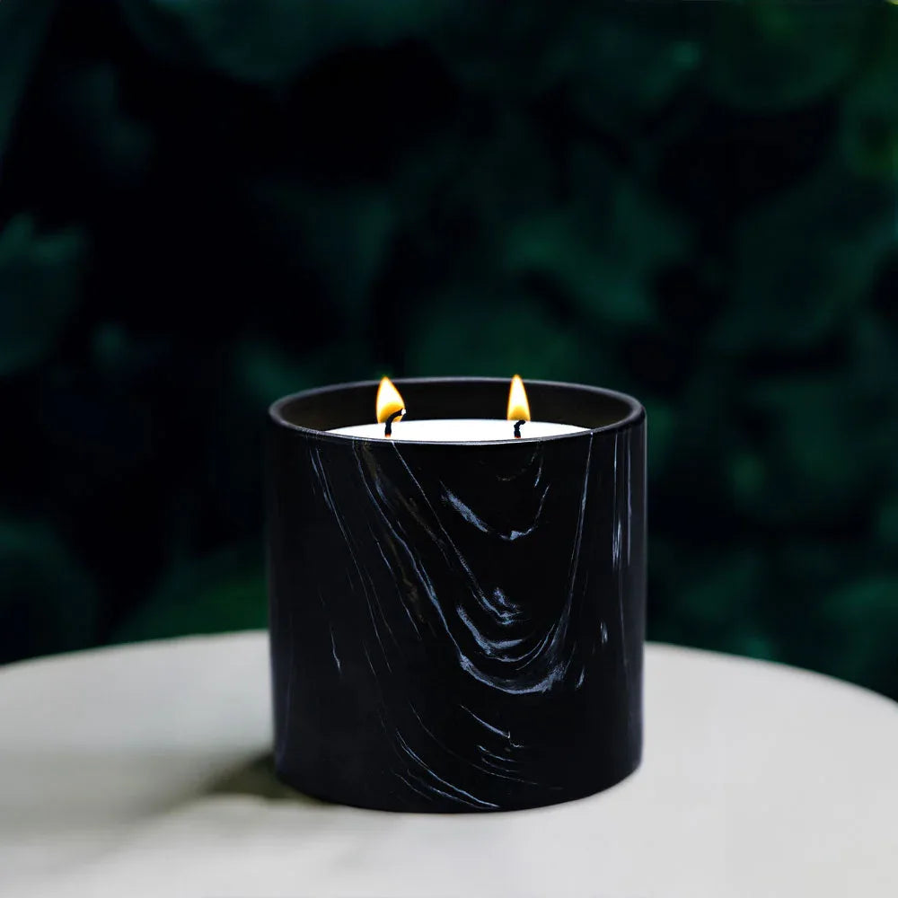 Marquina candle vessel surrounded by green leafy plants for natural aesthetic