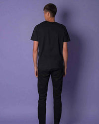 Model wearing black t-shirt showing back view with bee embroidery near neckline.
