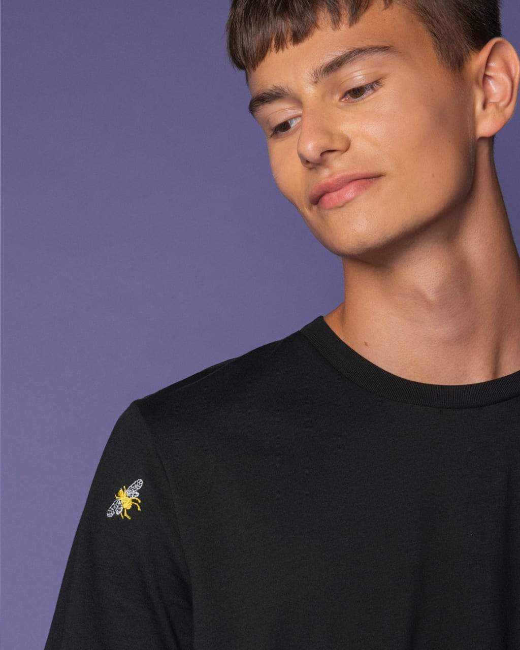 Close-up of embroidered bee detail on black t-shirt fabric.
