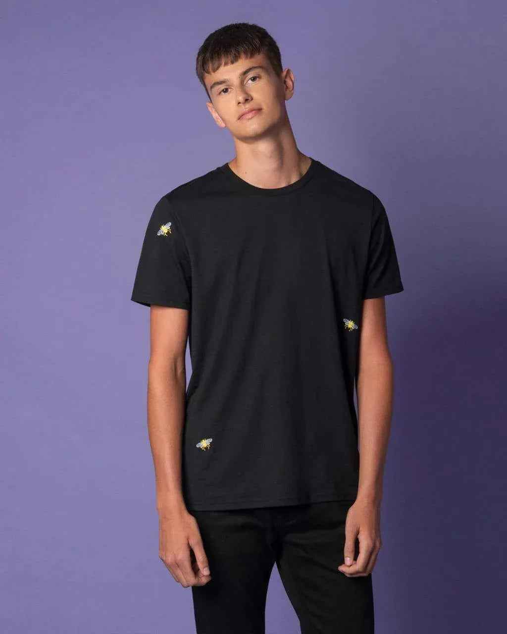 Model wearing black t-shirt with embroidered bee design on chest and back.