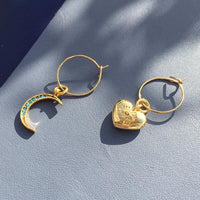 Turquoise crystal moon and chunky heart charm earrings in mini hoop style on light background.