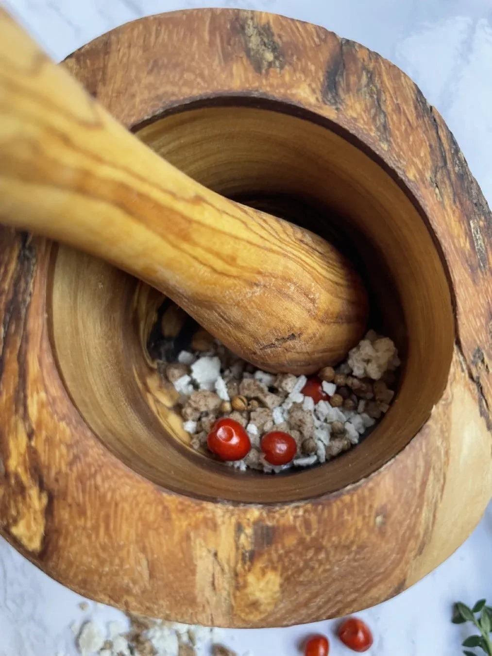 Rustic olive wood mortar and pestle set with rich wood grain on white background.