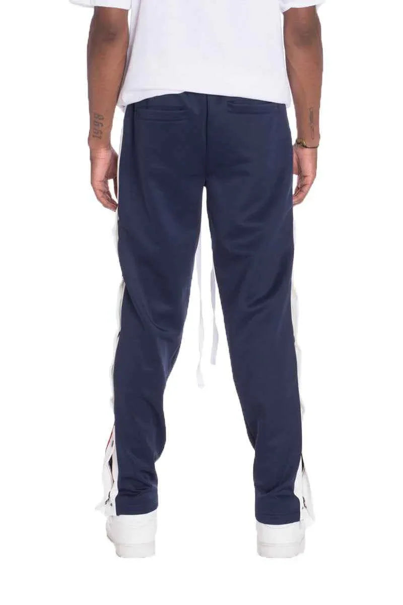 Back view of navy track pants featuring a straight fit and single back pocket with snap buttons.