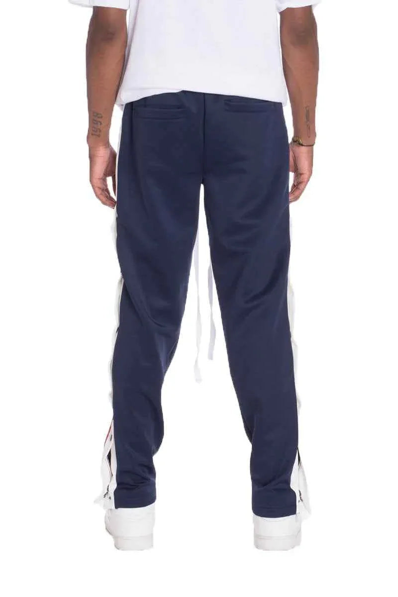 Back view of navy track pants featuring a straight fit and single back pocket with snap buttons.