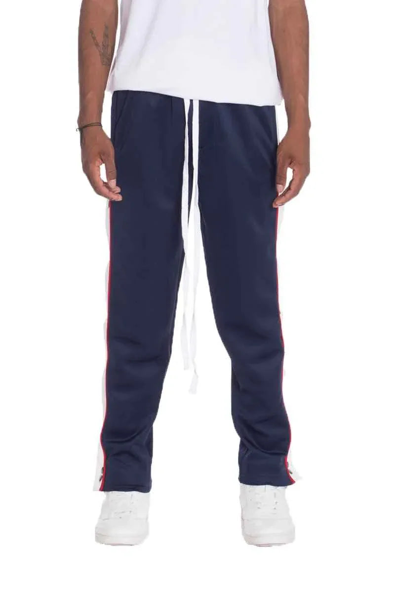Model wearing navy snap button track pants showing side snap button detailing.