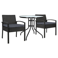 Two wicker garden patio chairs with beige cushions around a glass-top outdoor table.