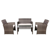 Two-seater rattan outdoor sofa with removable gray cushions placed beside matching armchair on wooden deck.