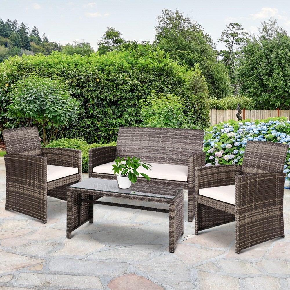 Rattan outdoor furniture set arranged on wooden deck with cushions and glass table, styled for patio.